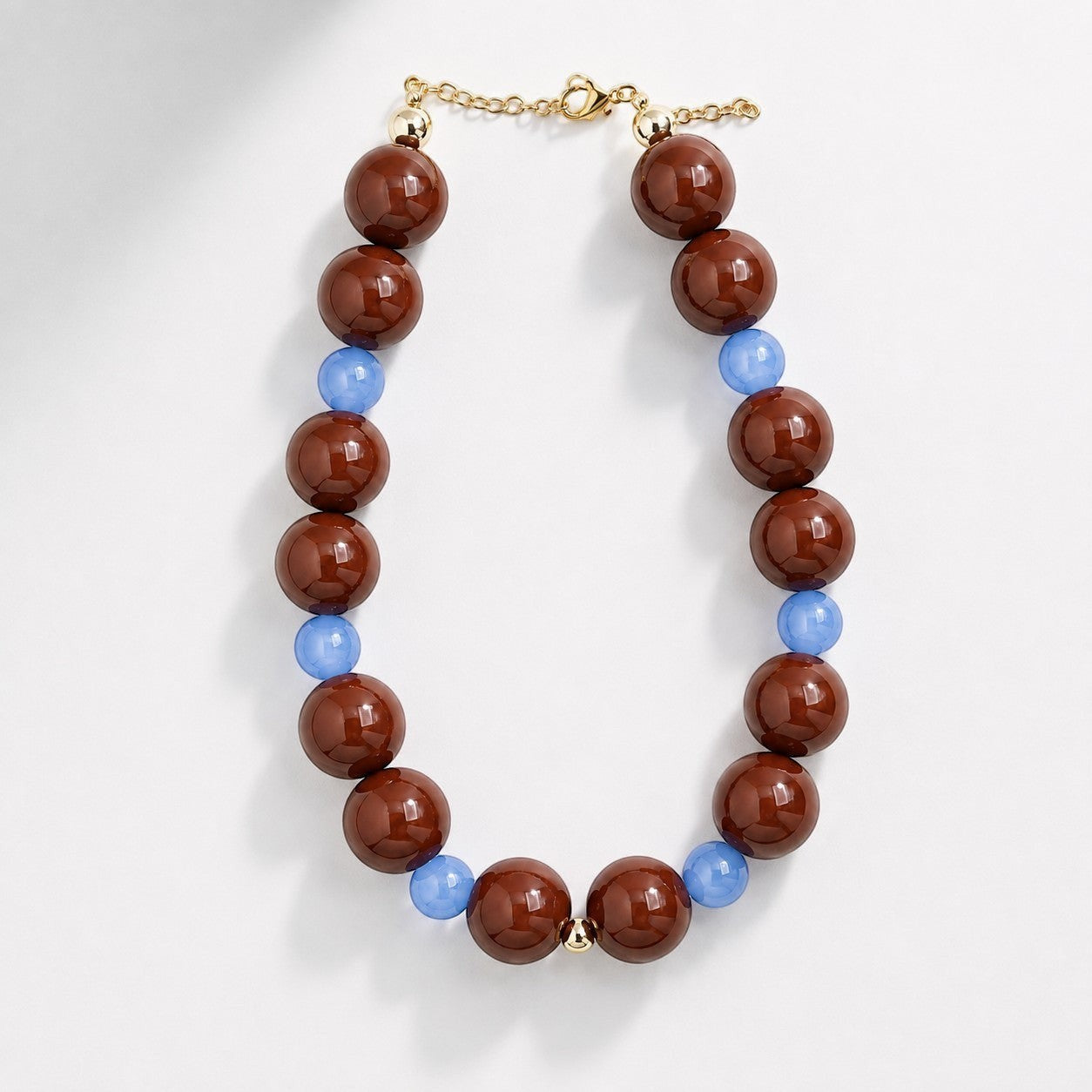 Robyn by design statement necklace with glossy chocolate brown and translucent periwinkle blue beads and gold hardware.