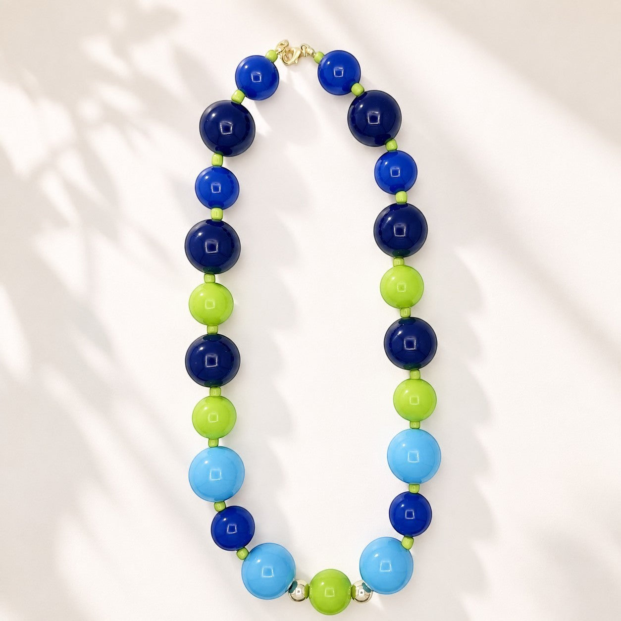 Robyn by design statement necklace featuring polished navy, electric blue, sky blue, and lime green spherical beads.
