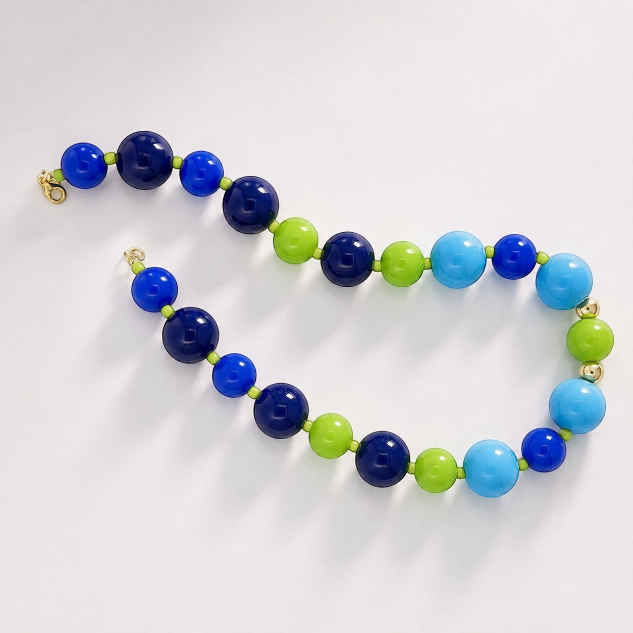 Robyn by design statement necklace featuring polished navy, electric blue, sky blue, and lime green spherical beads.